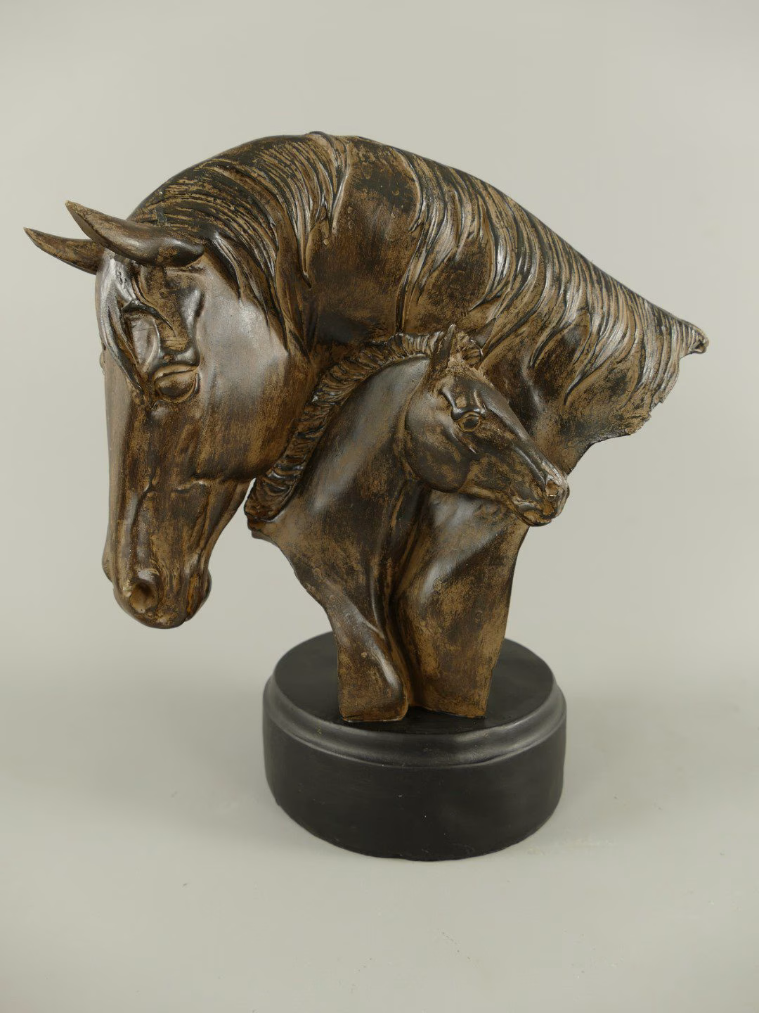 Paardenhoofd polystone bronskleur 2 Paardenhoofd polystone bruin/gekleurd hout. Het beeld toont twee hoofden: een moeder en haar veulen, die op een elegante sokkel rusten.